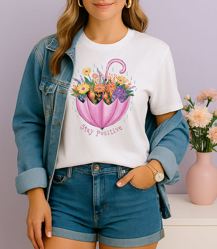 Woman wearing white Stay Positive T-shirt with pink umbrella floral design, handmade organic cotton uplifting fashion tee