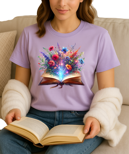 Person wearing a purple t-shirt with a colorful floral design of an open book, holding an open book.