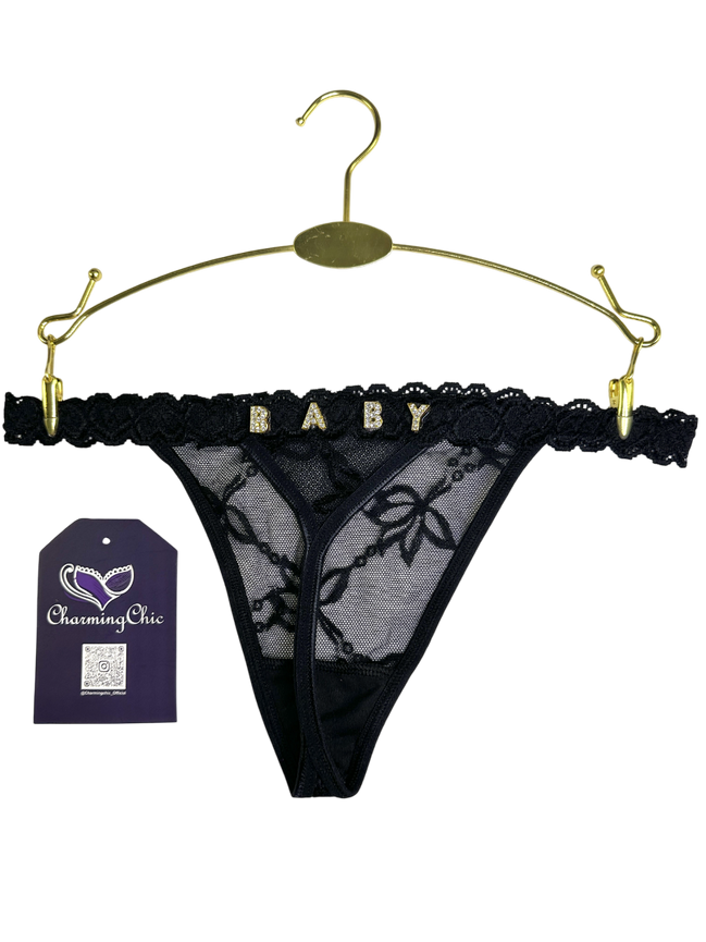 Black lace thong on a gold hanger with 'Charming Chic' tag.