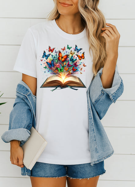 Person wearing a white t-shirt with a colorful butterfly design and an open book, standing against a white background.