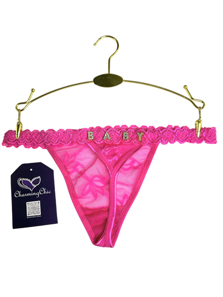 Pink lace thong with 'BABY' text on a gold hanger against a white background