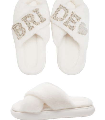 Pair of white slippers with 'Bride' and heart designs on a white background